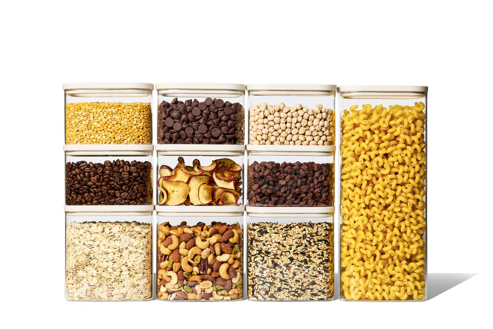 Naked Kitchen 20-piece glass countertop set with cream lids holding pantry staples including pasta, grains, nuts and coffee