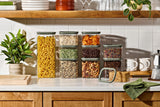 Naked Kitchen glass canisters with green lids organizing pasta, grains and nuts on a styled kitchen counter