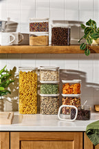 Vertical lifestyle shot of Naked Kitchen glass canisters filled with dry goods on a kitchen counter and shelf with plants
