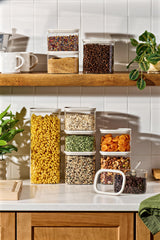 Vertical lifestyle shot of Naked Kitchen glass canisters filled with dry goods on a kitchen counter and shelf with plants