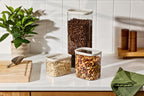 Trio of Naked Kitchen glass canisters holding coffee beans, oats and mixed nuts styled on a kitchen counter